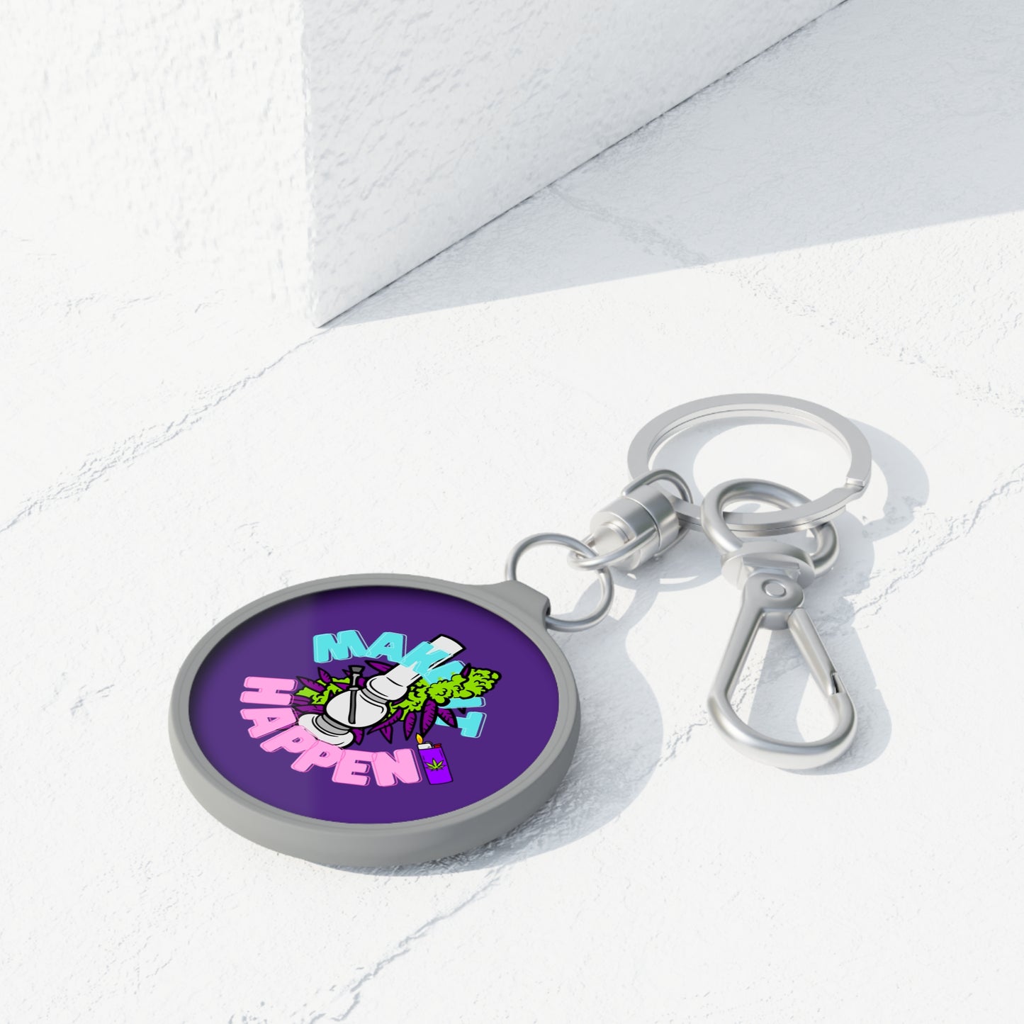 A Make It Happen Cannabis Keyring Tag with a cartoon graphic that reads "make it happen" placed on a white surface with angular shadows, featuring quality hardware fitting.