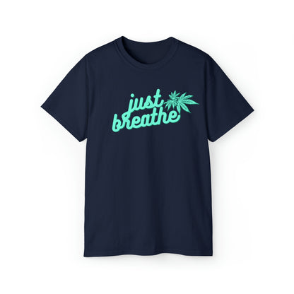 A **Just Breathe Cannabis Tee** with the text "Just Breathe" in light blue cursive letters and a cannabis leaf design on the front, perfect for those who embrace relaxation.