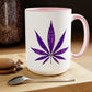 A Purple Haze Marijuana coffee mug with a pink handle featuring a large Purple Haze Marijuana leaf design, placed on a wooden table beside coffee beans and a macaron.