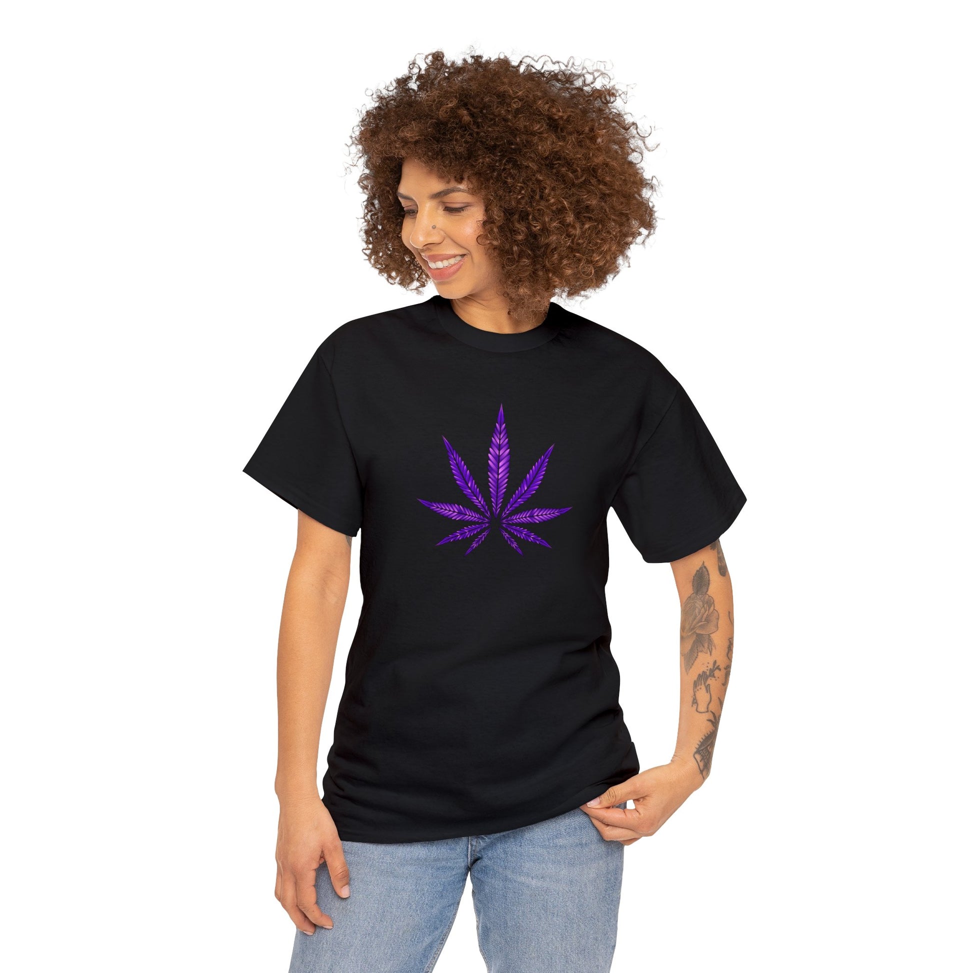 A person stands facing the camera, wearing a Purple Cannabis Leaf Tee. The individual has curly hair and a visible tattoo on their left arm.