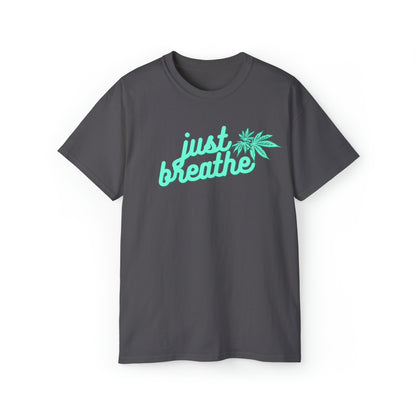 A dark gray Just Breathe Cannabis Tee featuring a "just breathe" message and a cannabis leaf graphic printed in light blue on the front, perfect for those moments of relaxation.