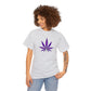 A woman is wearing a gray Purple Cannabis Leaf Tee with a vibrant purple cannabis leaf graphic on the front. She has curly hair and a visible tattoo on her left arm.
