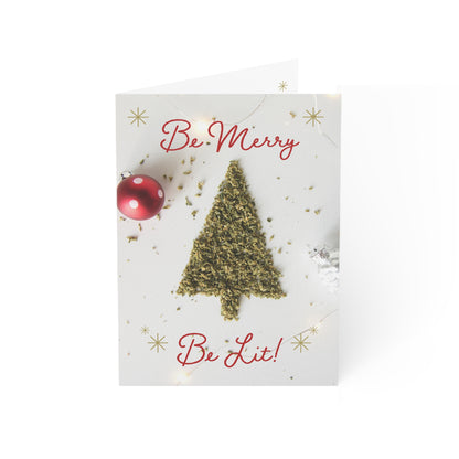 A holiday card showing a cannabis leaf tree with 'Be Merry Be Lit' text, accompanied by a red bauble and golden snowflakes, presents a unique take on festive greetings.