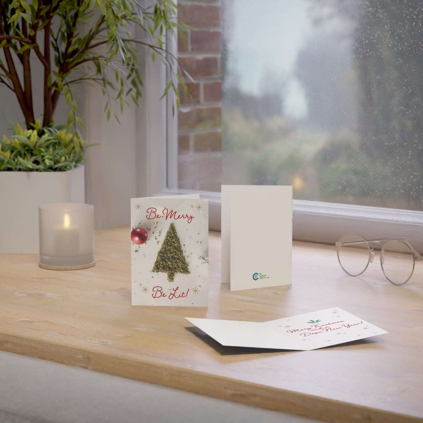 Be Merry Be Lit Christmas card being shown front, back, and inside laying on a window edge.