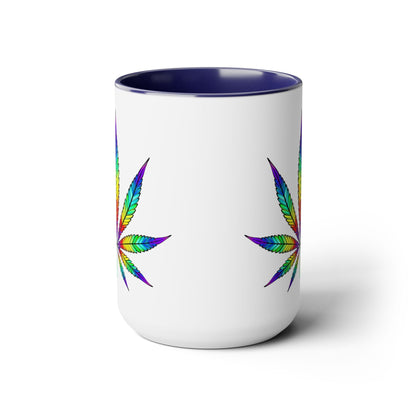 A white ceramic mug with a blue interior, featuring two colorful, rainbow-patterned cannabis leaves