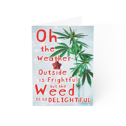 Weed is So Delightful Greeting Cards (1, 10, 30, and 50pcs) featuring a cannabis leaf with the text "oh the weather is frightful but the weed is so delightful" in a playful font, set against a blurred background printed on sustainable paper.