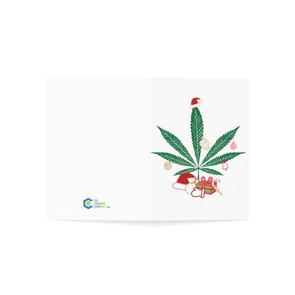 Open greeting card featuring a Mary Kushmas + Dope New Year Marijuana Tree adorned with Christmas decorations, including a Santa hat, gifts, and lights, printed on FSC certified paper, with a company logo on the bottom left.