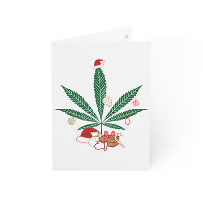 Mary Kushmas + Dope New Year Marijuana Tree Christmas Greeting Cards featuring a cannabis leaf decorated with Christmas ornaments, a Santa hat, and gifts at the base, set against a white background and printed on FSC certified paper.