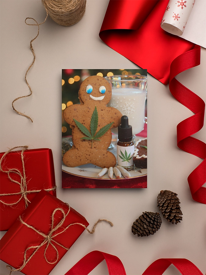 Stoner Holiday card of a Gingerbread Man with a pot leaf next to a tincture, joints, edible and milk surrounded by red ribbon and wrapping paper.