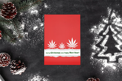 Have a Dope Holiday Merry Christmas Happy New Year Greeting Card with white text and leaf designs, surrounded by pine branches and pine cones on a dusty black background with a chalk-drawn Christmas tree.