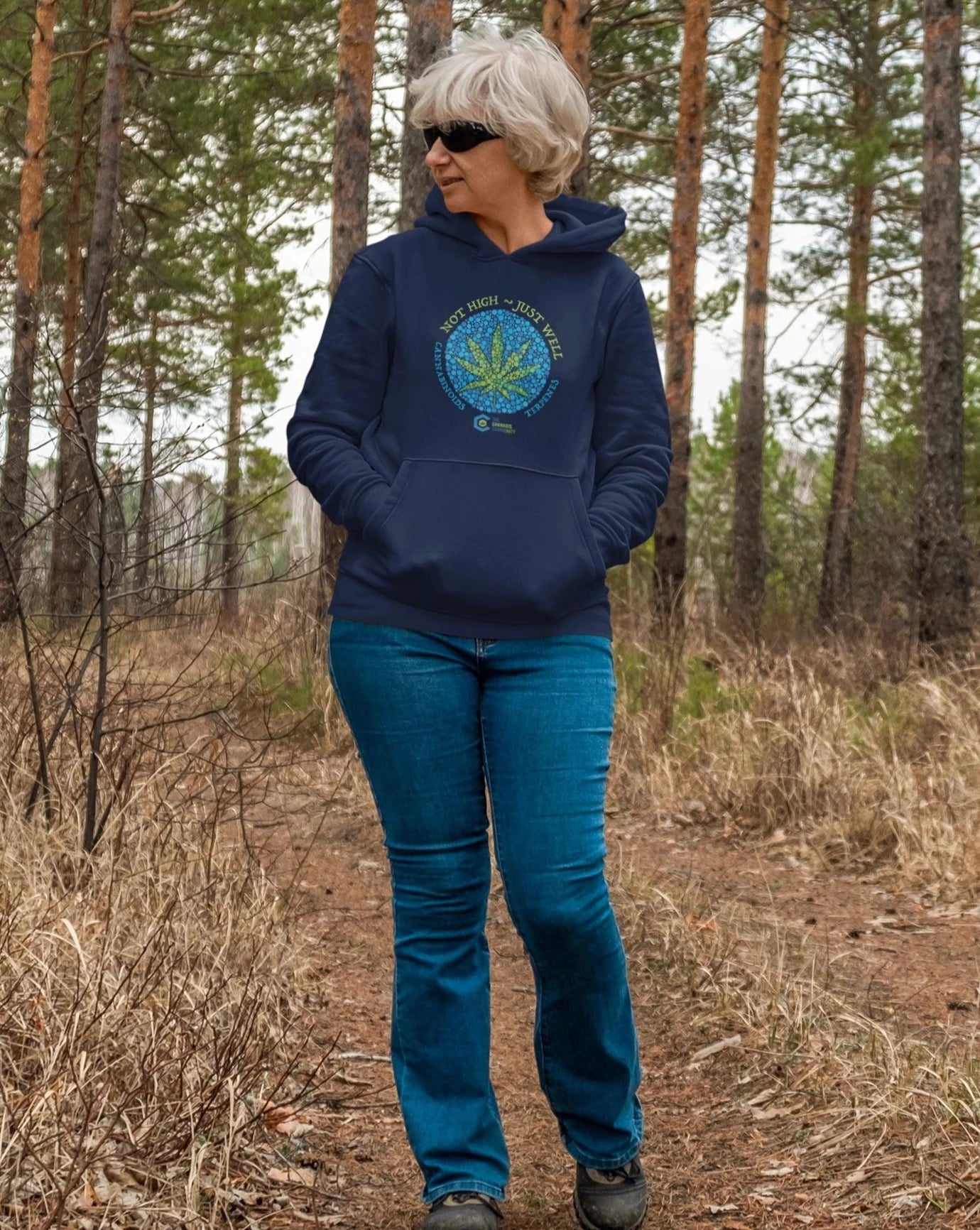 Woman wearing Not High Just Well Navy Hoodie walking through the woods