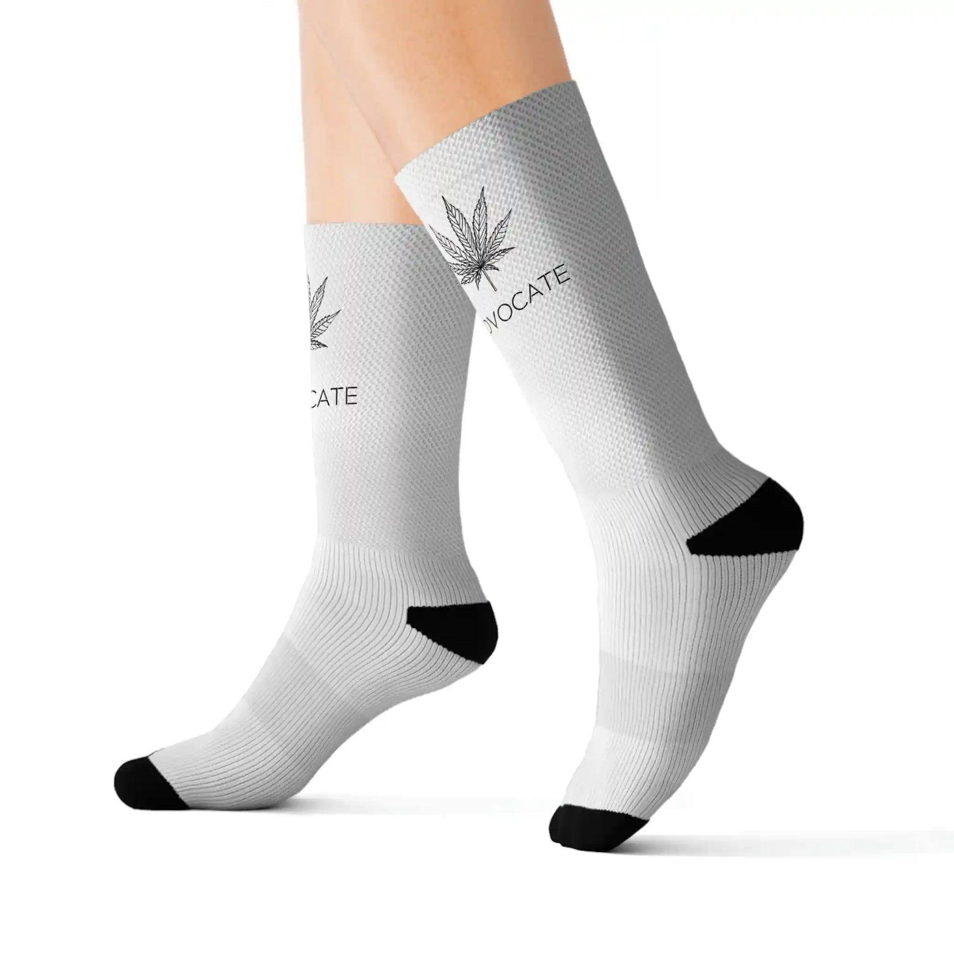 A closeup of a person wearing black and white weed socks that show a cannabis leaf on the top front of the sock with the words that read "advocate"
