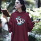 witch in the woods casting a spell wearing a maroon High Spirits Halloween Hoodie