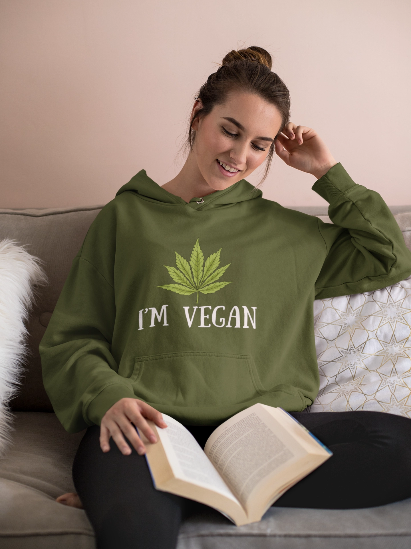 Woman reading wearing an I'm Vegan hoodie on the couch