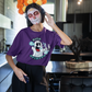 woman wearing a purple high spirits weed shirt with a day of the dead face mask while listing to music