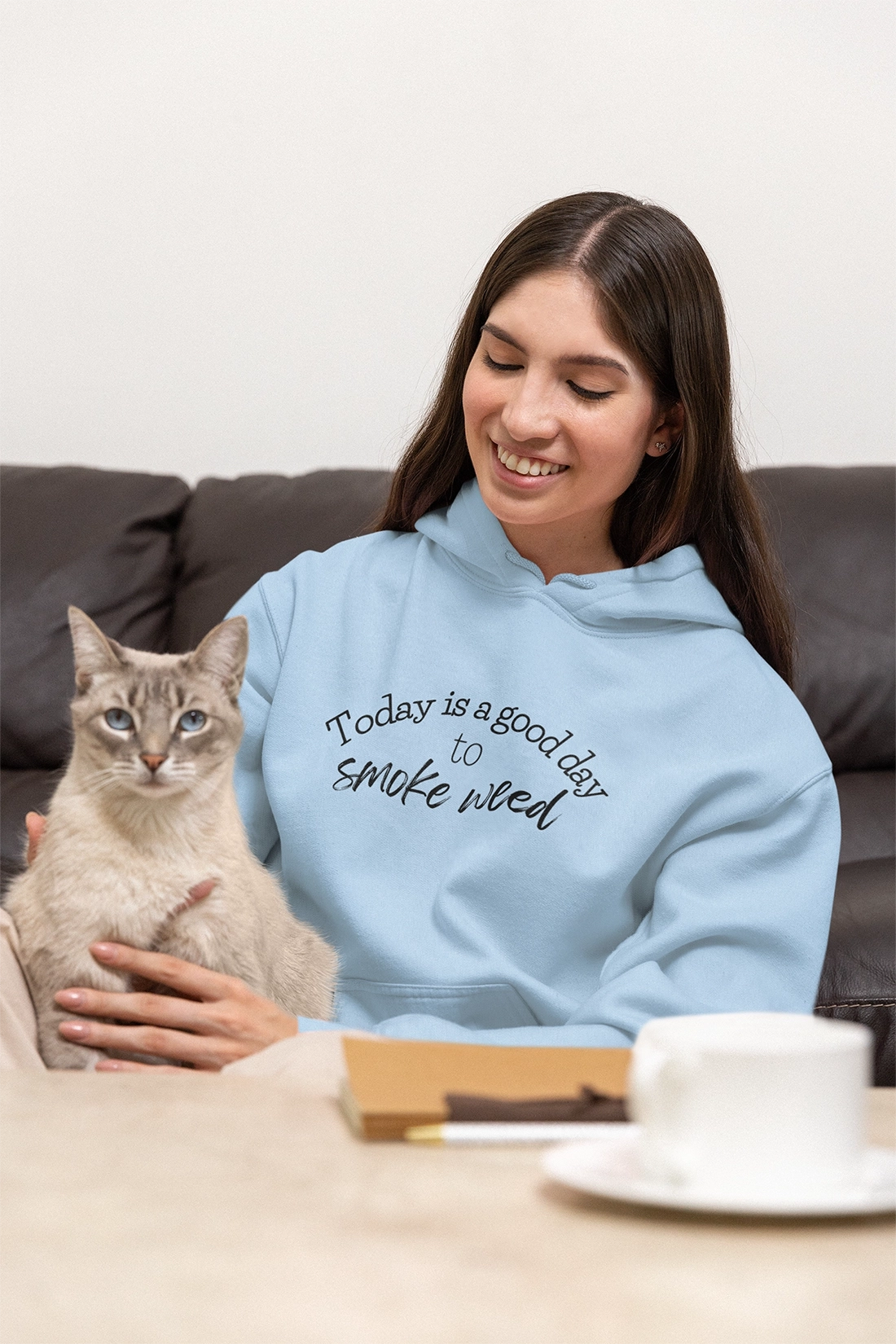 Woman at home with her cat wearing a light blue Today is a Good Day to Smoke Weed Hoodie