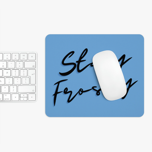 White computer mouse on a Stay Frosty Blue Mouse Pad with the words "stay focused" in black script, next to a white keyboard on a white surface.