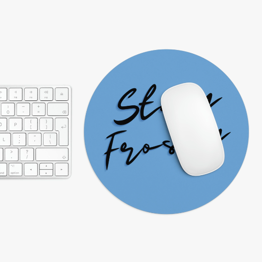 A white keyboard next to a Stay Frosty Blue Mouse Pad with a non-slip grip, featuring a white mouse and the words "stay focused" in black script.