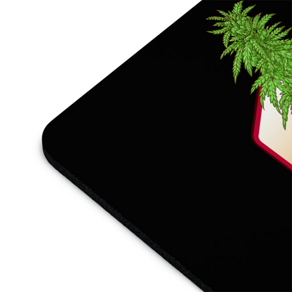 A corner of a sleek black electronic device with a Cannabis Plant Daddy Mouse Pad extending over it on a white background.