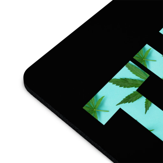 A close-up view of a corner of a THC Marijuana Black Mouse Pad featuring a design of green marijuana leaves on a turquoise background.