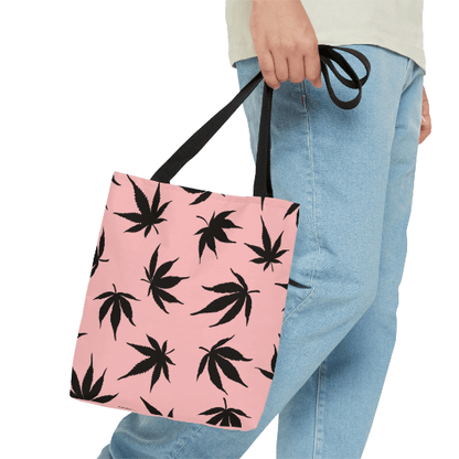 A person holding the Marijuana Leaves Pink Tote Bag, featuring trendy black marijuana leaves and proudly crafted in the USA.