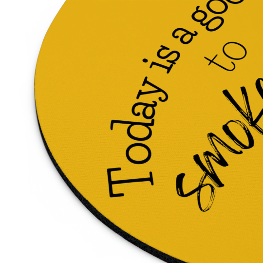 Round vibrant yellow mouse pad with the text "today is a good day to smile" in black cursive writing, partial view on a white surface.