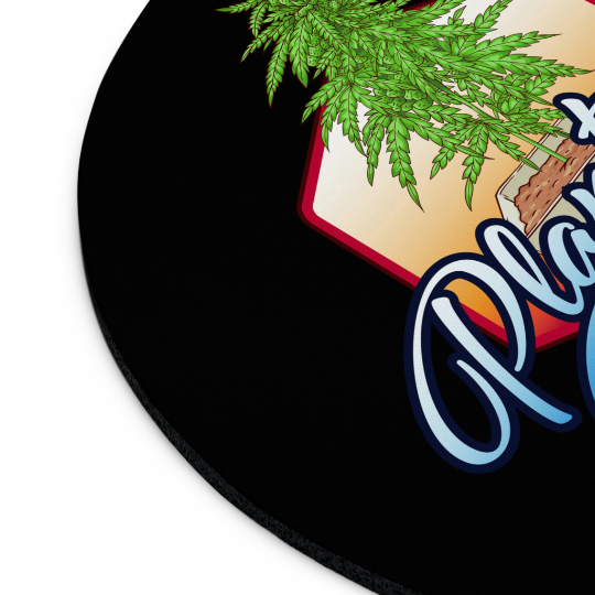 Round mouse pad with non-slip base, featuring a stylized Cannabis Plant Daddy Mouse Pad design and text elements, slight view of a book's edge at the top.