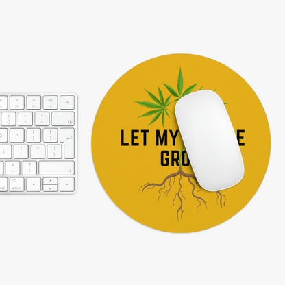 Top view of a desk with a white keyboard, a white mouse resting on a round Let My People Grow Yellow Mousepad featuring a cannabis leaf design and the text "Let My People Grow.