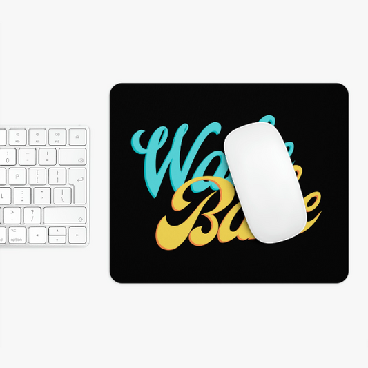 A white computer mouse on a black Wake and Bake Cannabis mouse pad with cursive "work hard" text, next to a white keyboard on a white surface.
