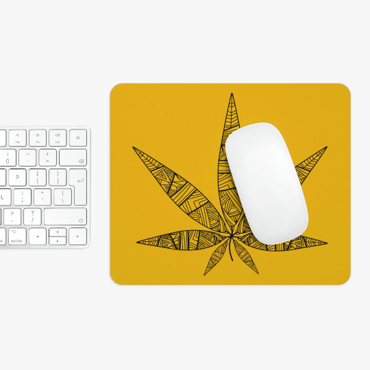 White computer mouse on a Tribal Weed Leaf Yellow Mouse Pad with a tribal cannabis leaf design, next to a white keyboard on a white surface.