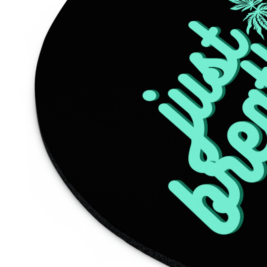 Round Just Breathe Cannabis black mouse pad with the phrase "just breathe" in stylized green script, accompanied by a small green leaf design in the upper right corner.