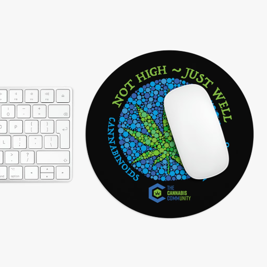 A white computer mouse and keyboard placed on a round, non-slip Not High, Just Well Black Mouse Pad with a design promoting cannabinoids, featuring text "not high ~ just well" and a blue and green molecular graphic.