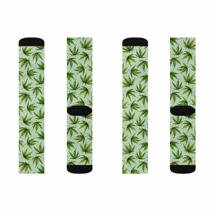 two pairs of green and black weed socks with weed leaves all over a green background including a black toe and heel