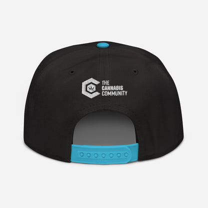 Back view of a black structured Golden Goat Cannabis Snapback Hat with a turquoise button, featuring a white and gray "the cannabis community" logo embroidered above the adjustable strap.