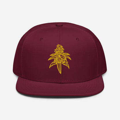 A Golden Goat Cannabis Snapback Hat with a yellow embroidered design of a cannabis leaf on the high-profile front.