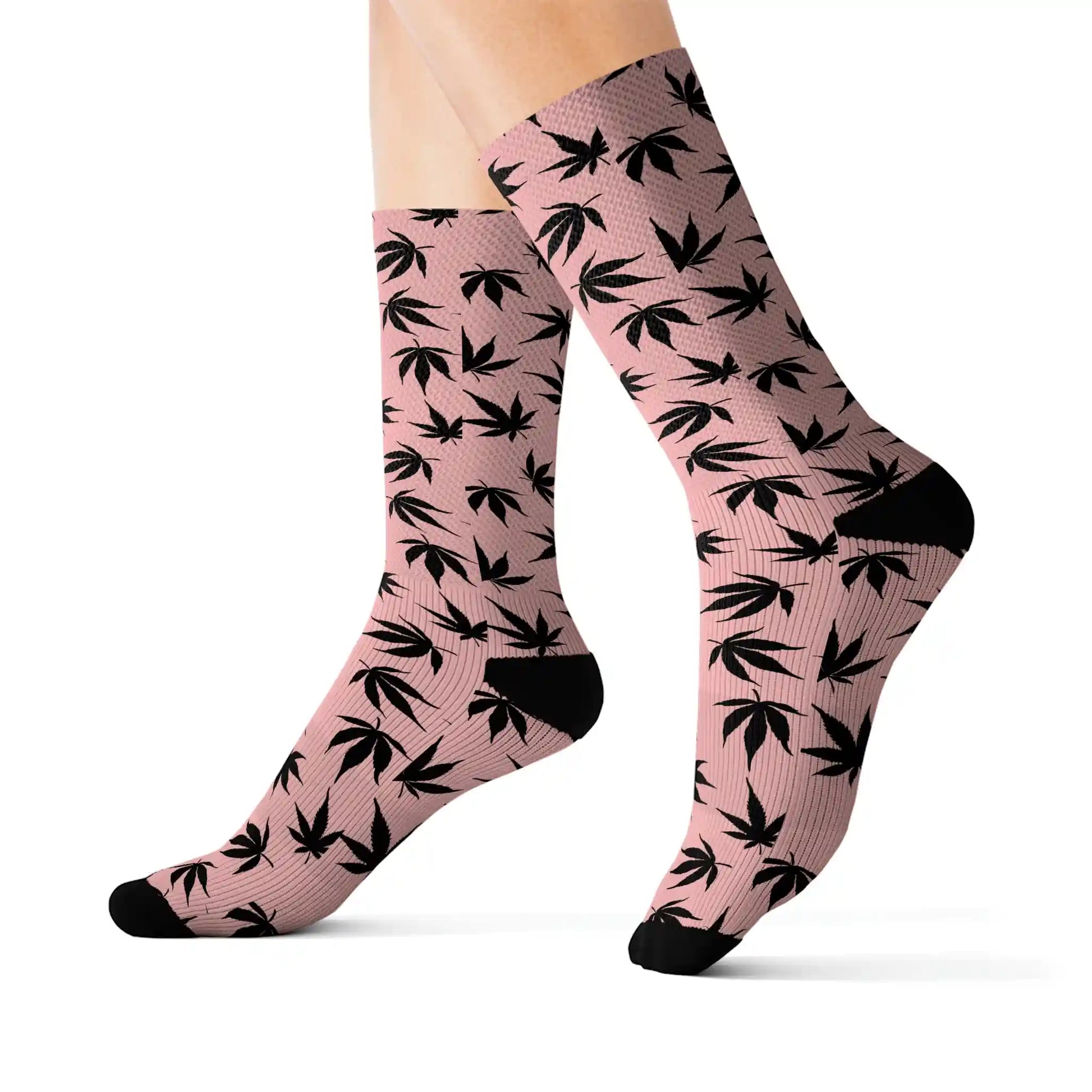 a close up of a stylish pair of pink and black marijuana socks with black cannabis leaves all over