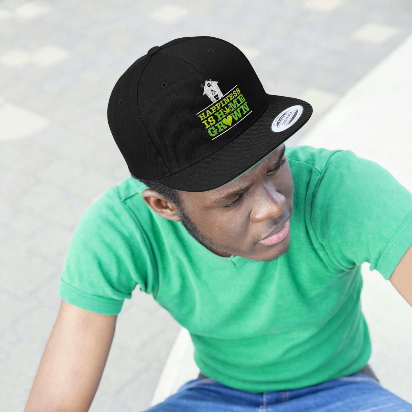 Photo of a young man staring while wearing the all black Happiness Is Homegrown Weed Snapback Hat with picture of a white house above the lettering