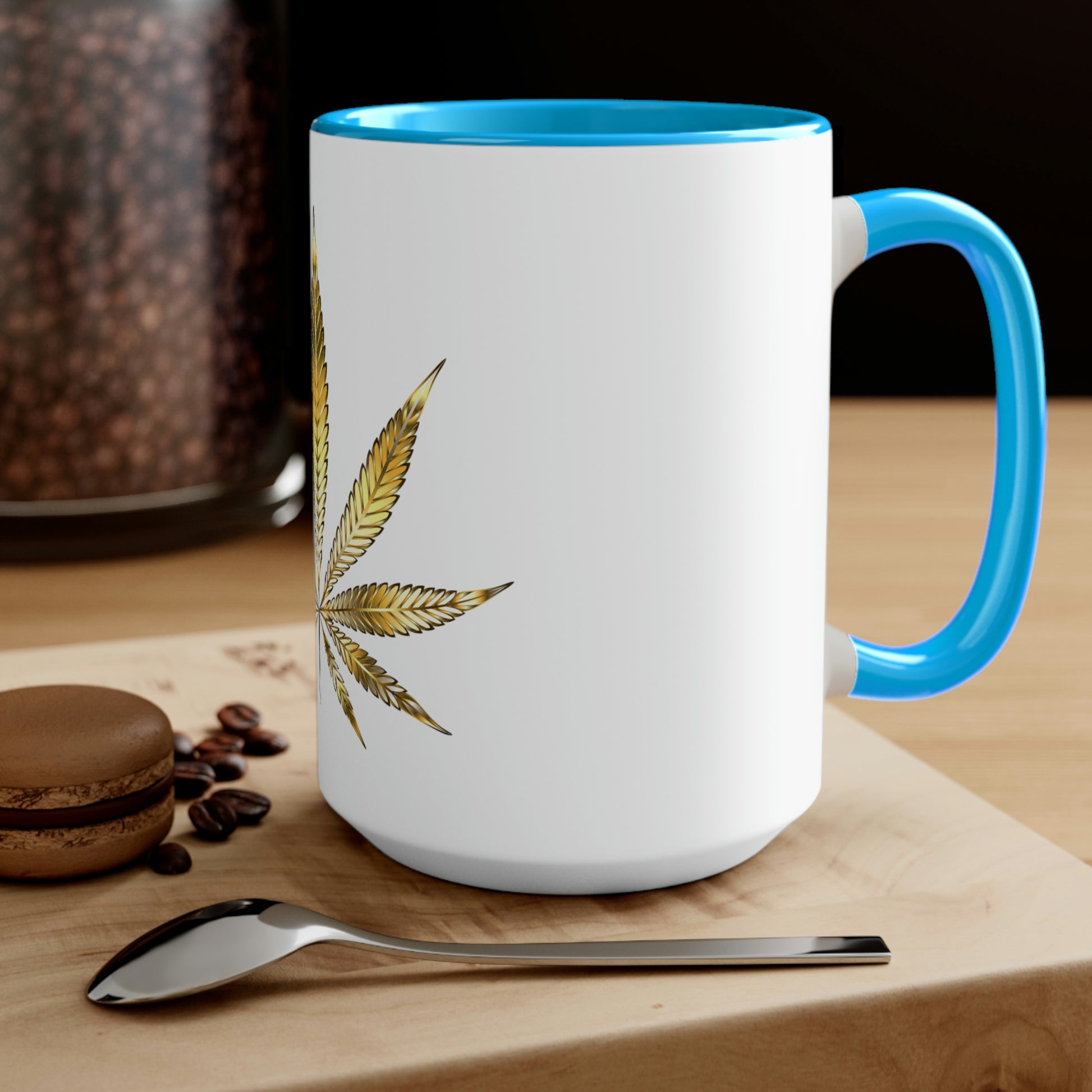 A white cannabis mug with a light blue interior featuring a bright gold weed leaf on the front center, sitting on a wood base.