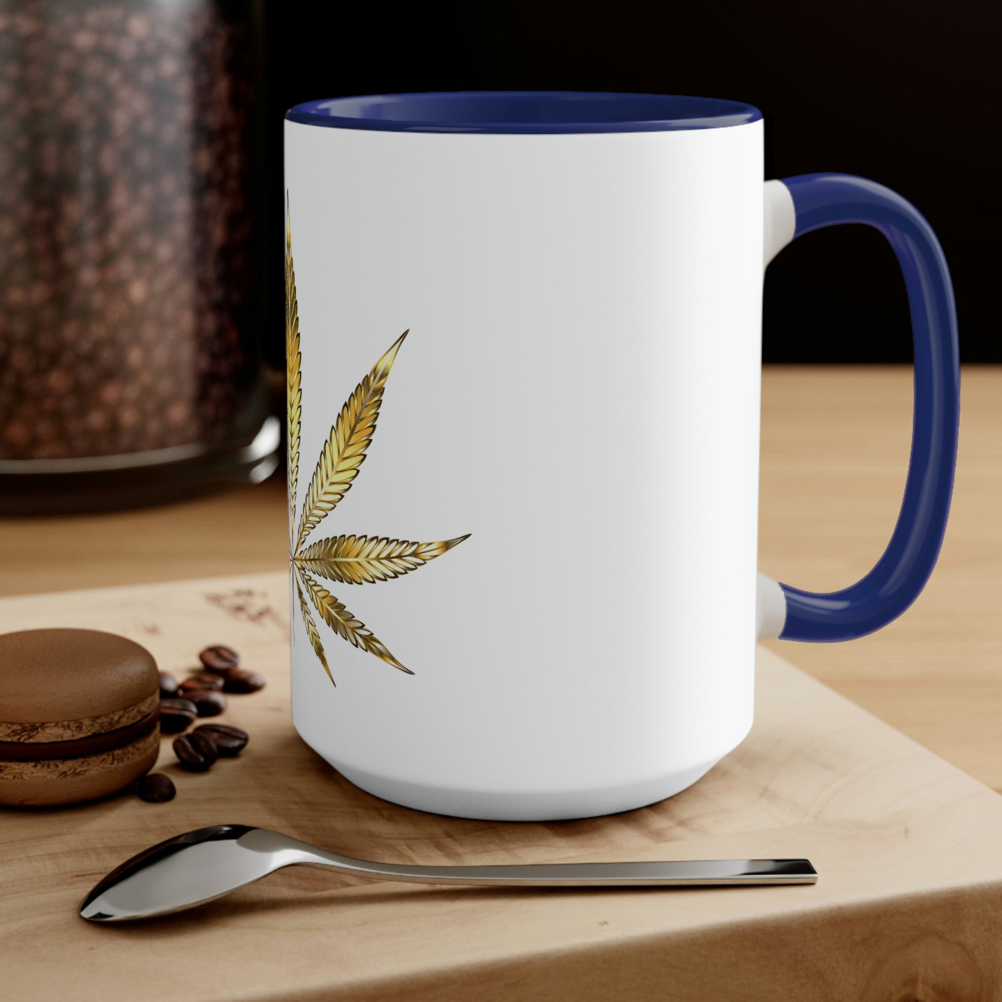 A white cannabis mug with navy blue interior featuring a bright gold weed leaf on the front center, sitting on a wood base.