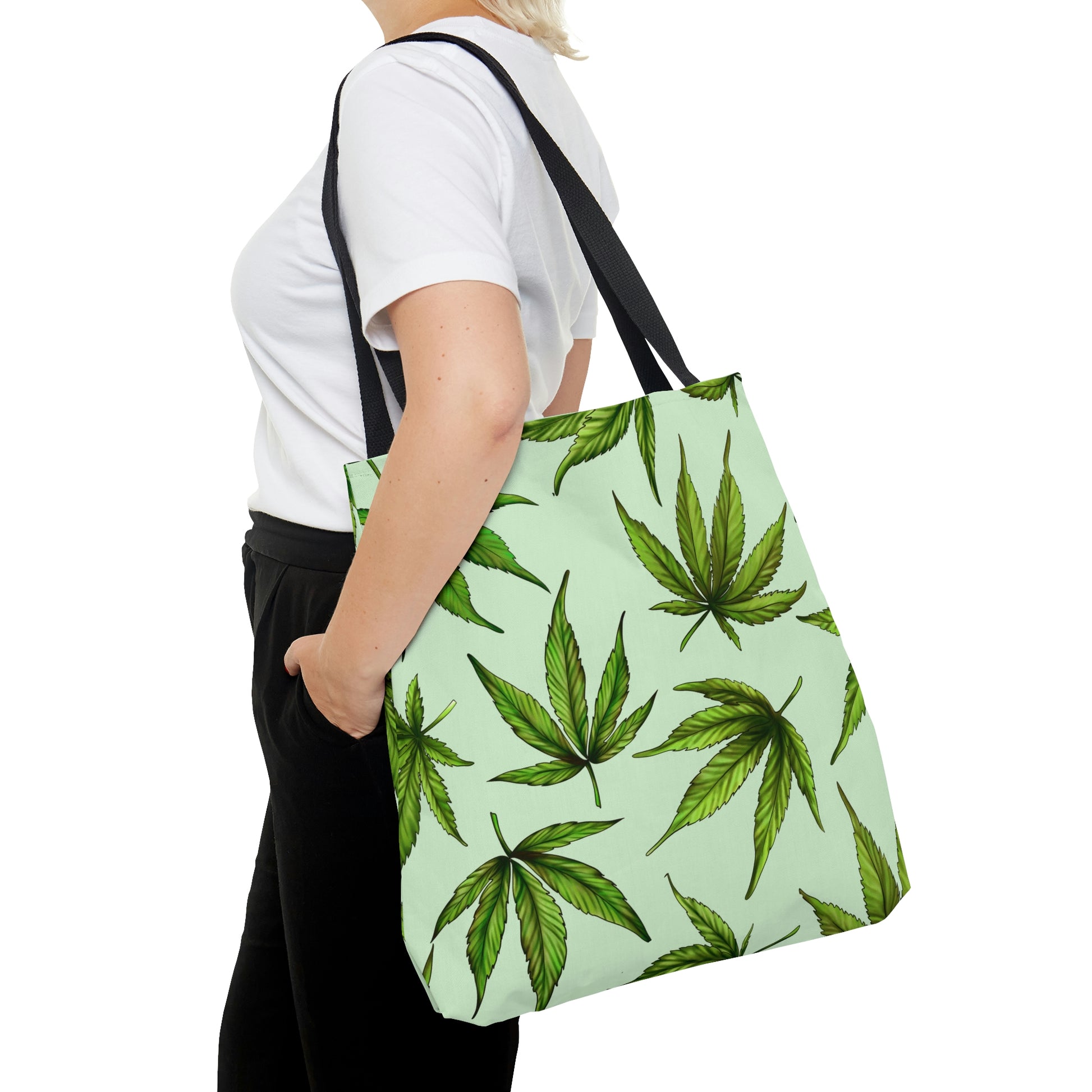 A woman with blonde hair carries the Marijuana Leaves Green Tote Bag on her left shoukder