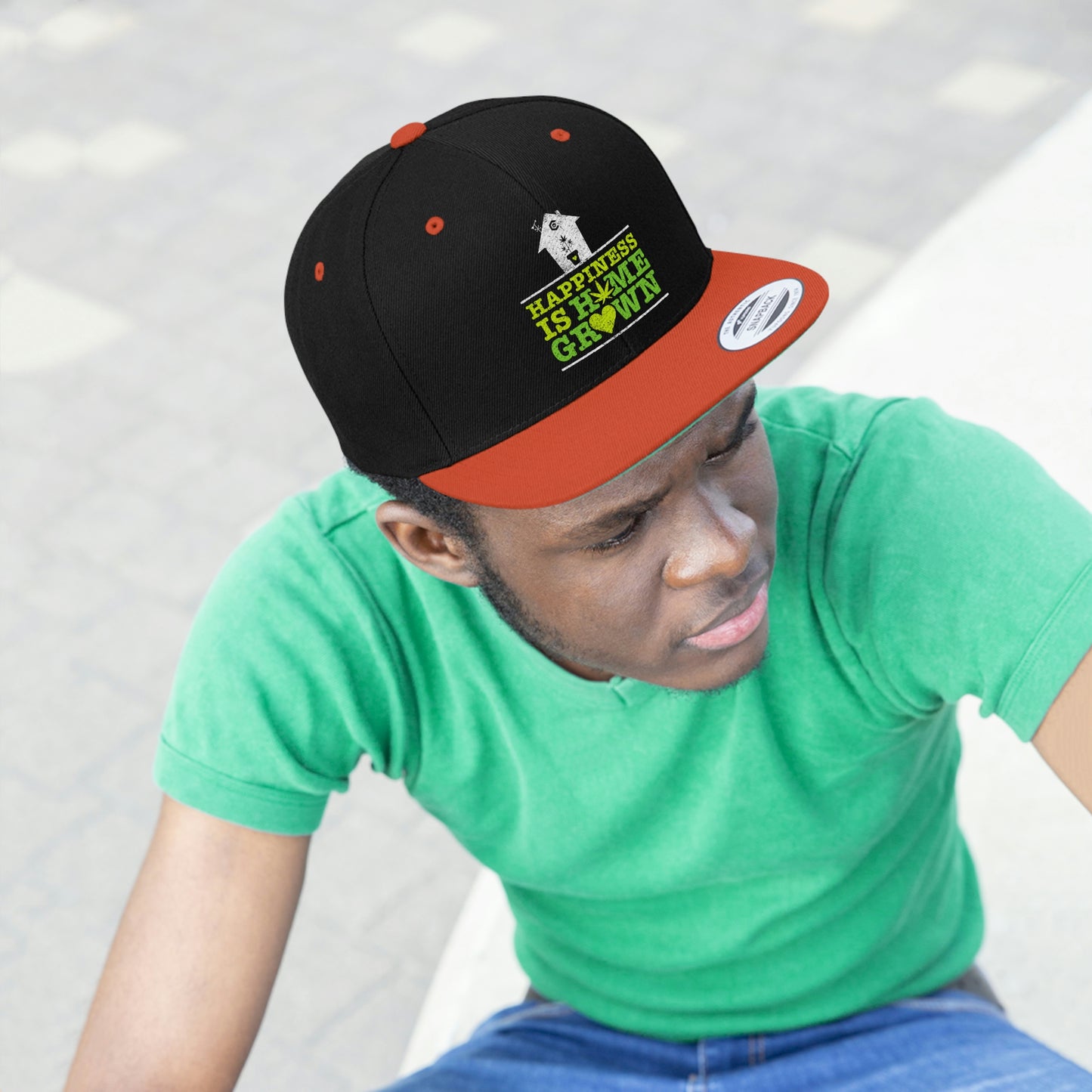 Photo of a young man glaring while wearing the orange and black Happiness Is Homegrown Weed Snapback Hat with picture of a white house above the lettering
