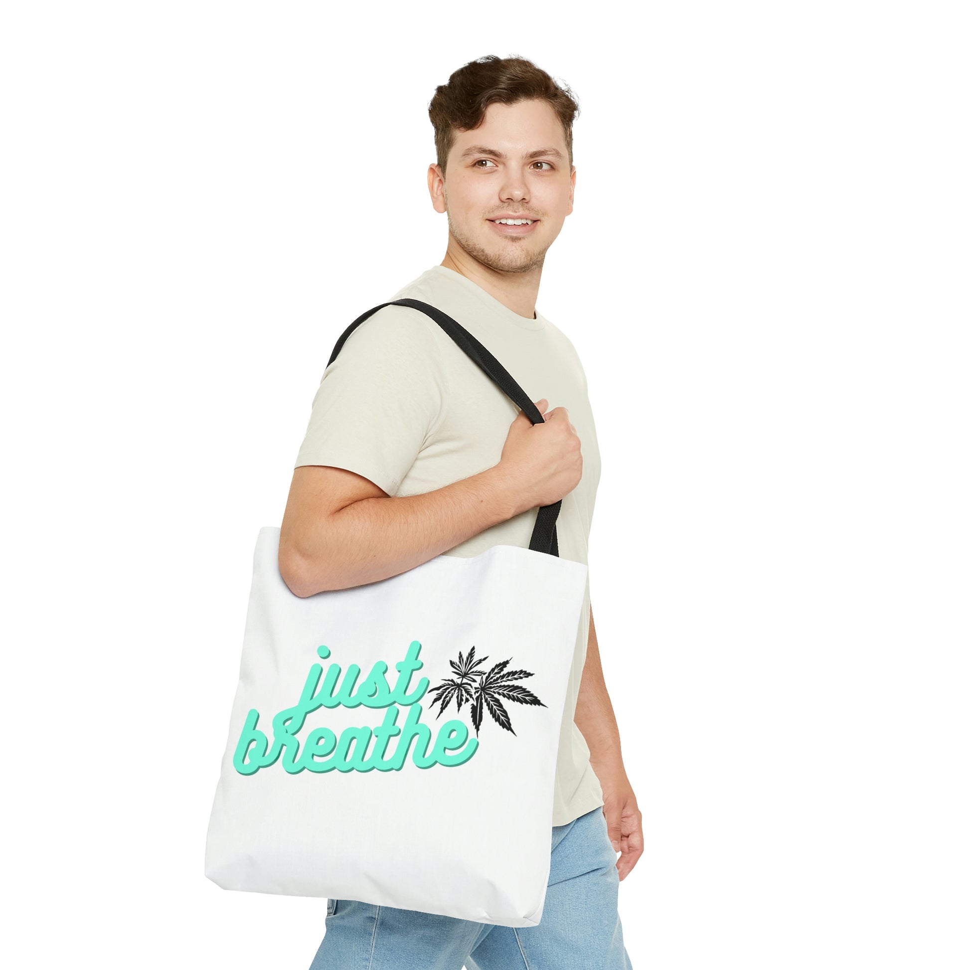 A man is looking curiously off to the side as he shows off the Just Breathe Cannabis Tote Bag