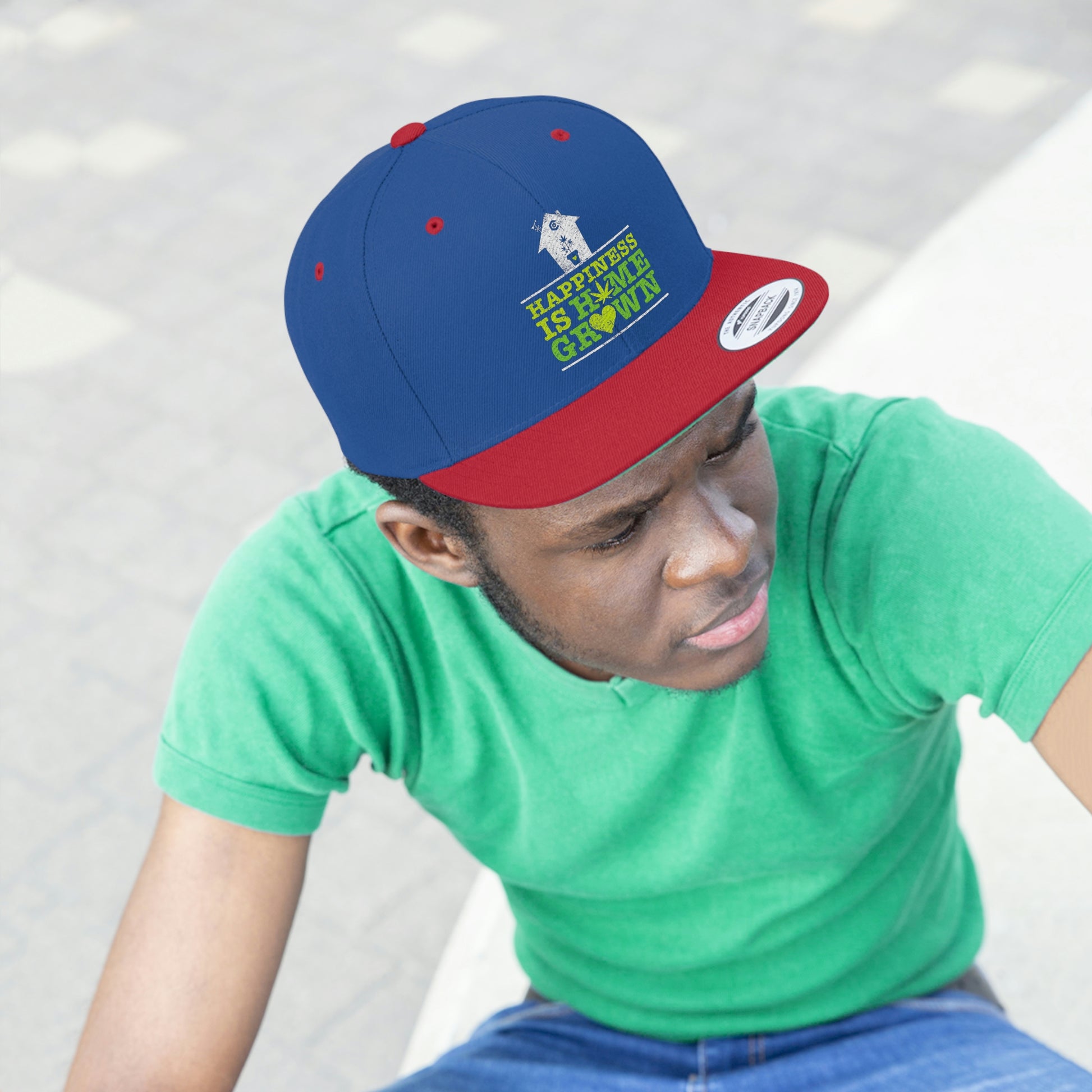 Photo of a young man watching while wearing the red and blue Happiness Is Homegrown Weed Snapback Hat with picture of a white house above the lettering