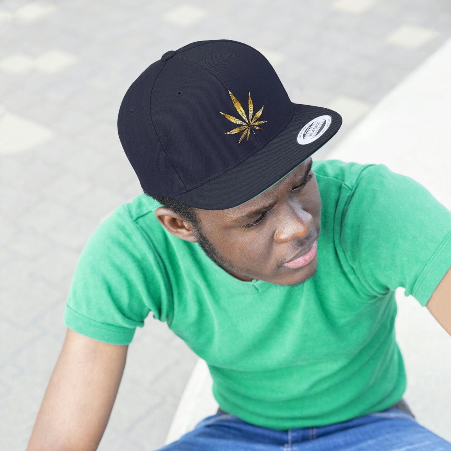 Picture of a young man watching from a distance in a green t shirt with the navy blue Gold Marijuana Leaf Snapback Hat