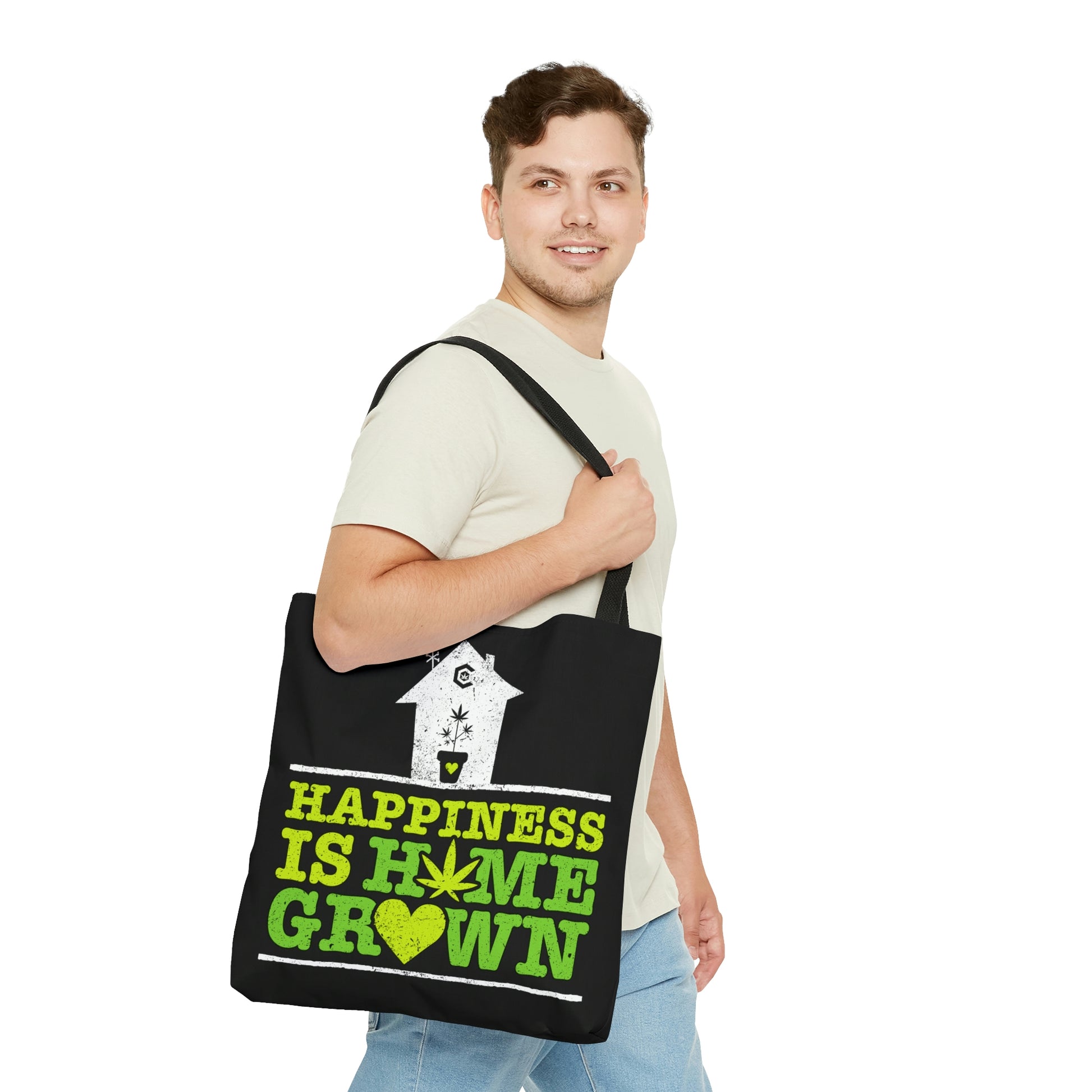 A man is looking onward as he happily wears the Happiness Is Homegrown Black Marijuana Tote Bag
