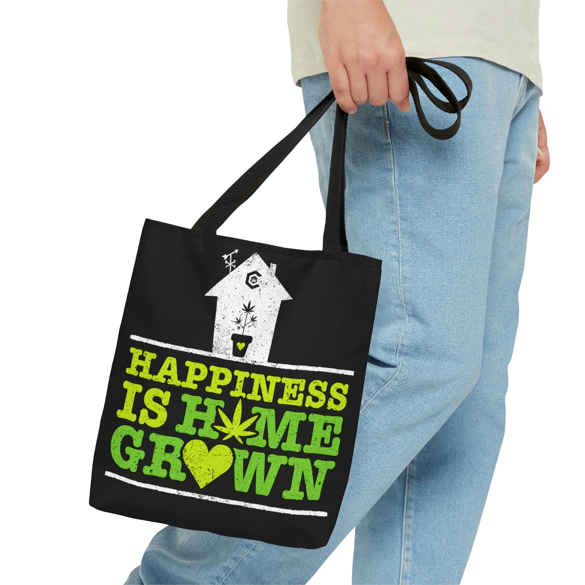 A man is holding at his side the Happiness Is Homegrown Black Marijuana Tote Bag