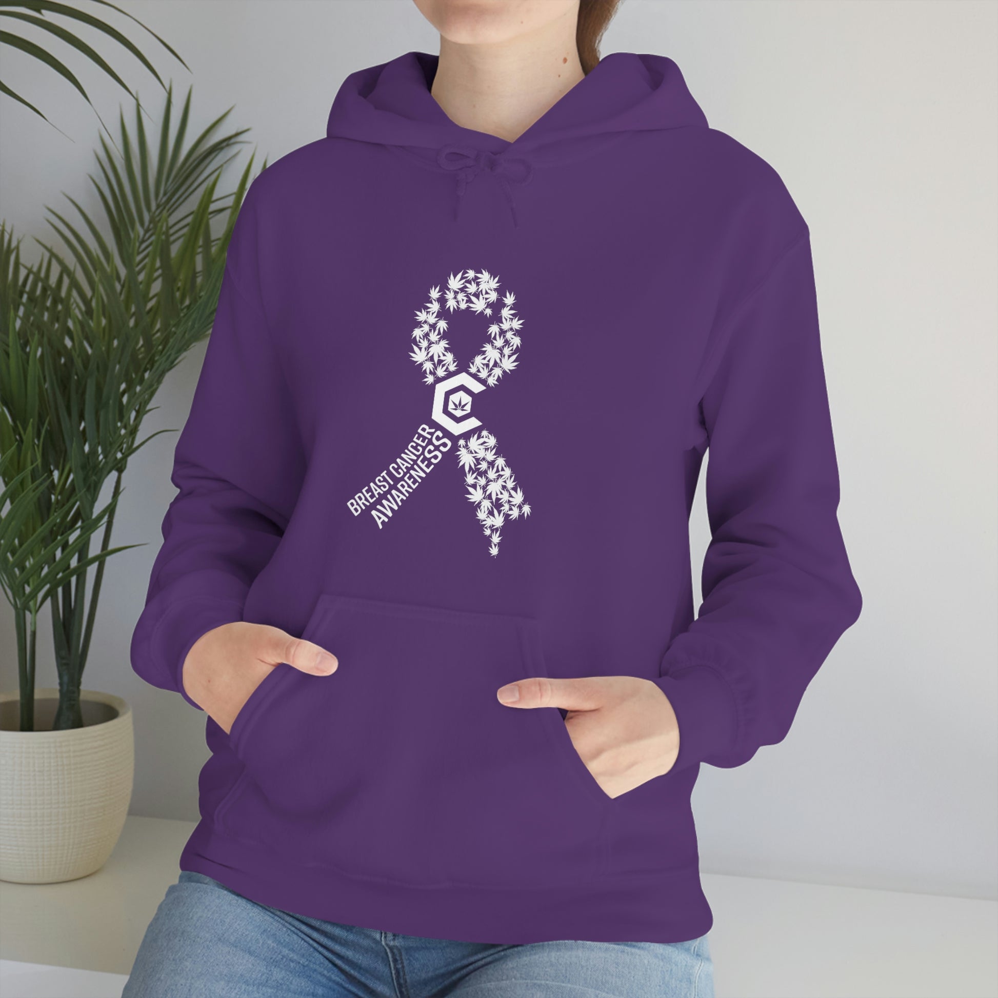 a woman wearing a purple Breast Cancer Awareness Cannabis Pullover Hoodie with an awareness ribbon on it.