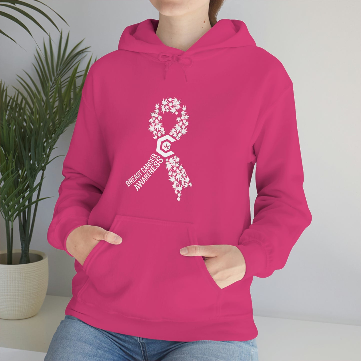 a woman wearing a pink Breast Cancer Awareness Cannabis Pullover Hoodie with a cancer ribbon on it.