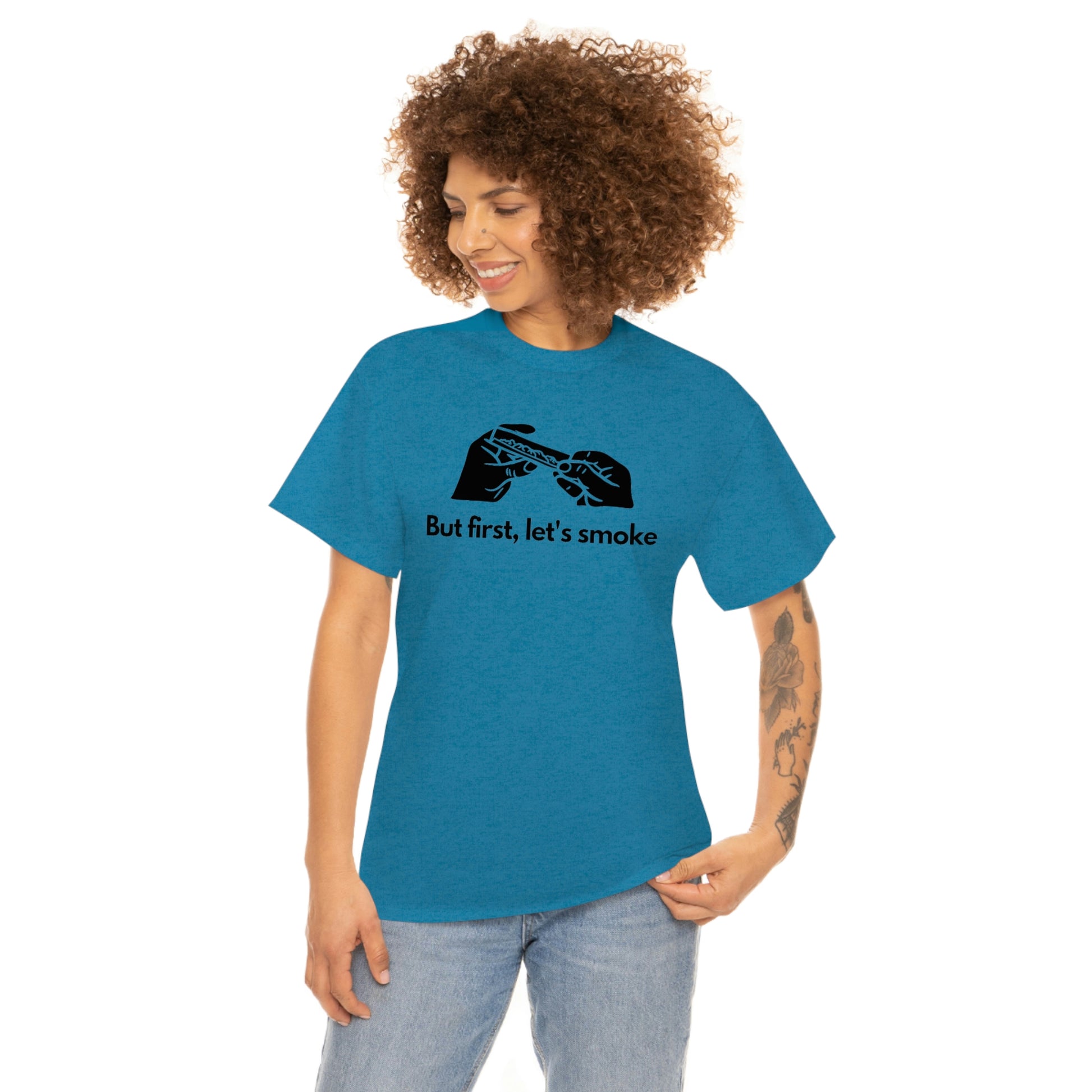 A woman wearing a turquoise t-shirt that says "But First, Let's Smoke Tee.