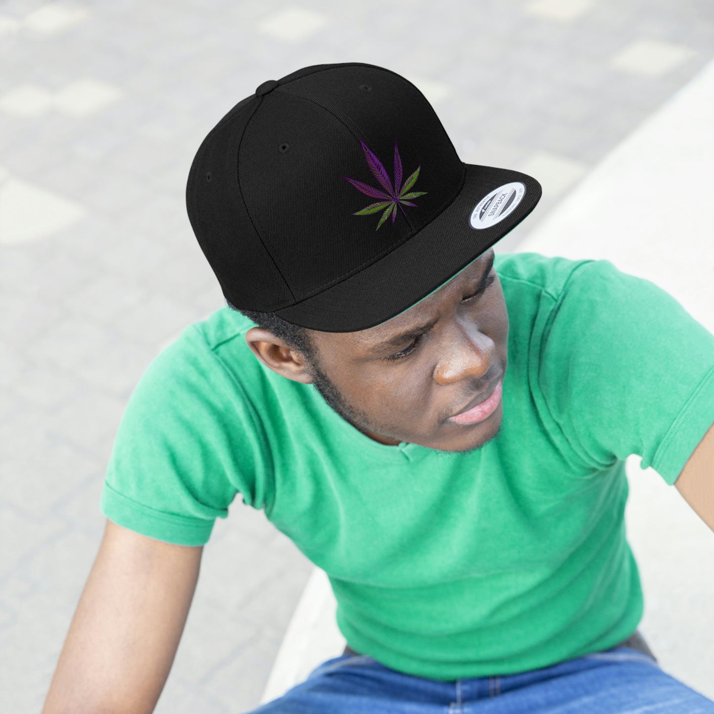 A young man in a green t shirt looks toward the void in the all black Purple Cannabis Leaf Snapback Hat